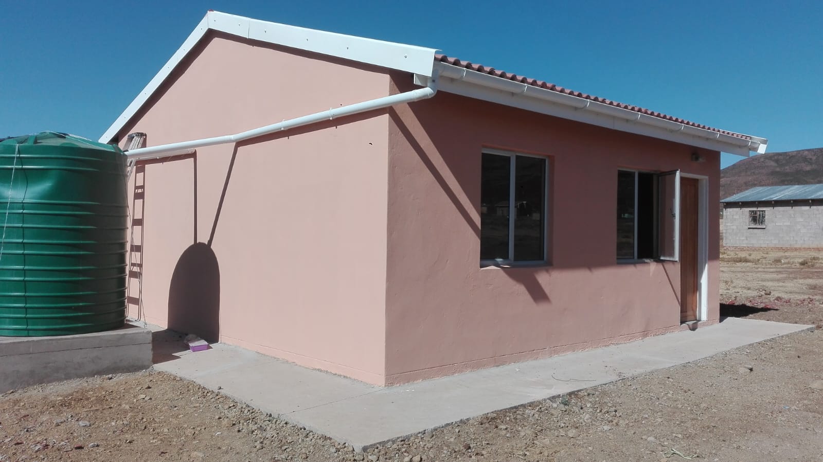 Completed EPHP housing unit at Cala with water tank and mountain backdrop
